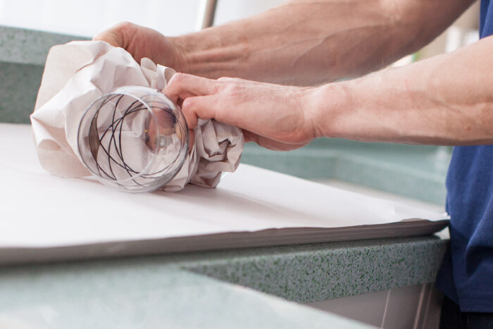 Ballards employee wrapping glass with paper during house move