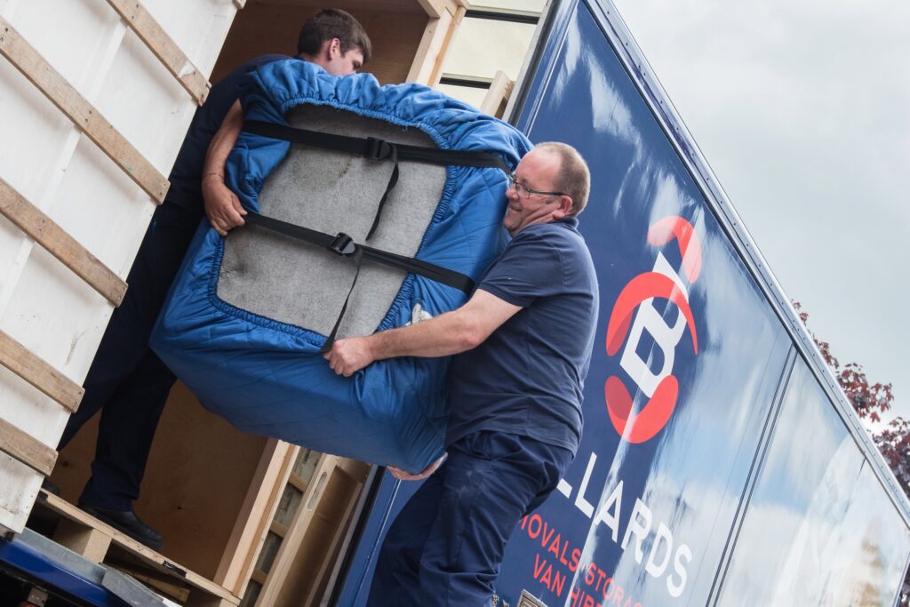 Two men carrying furniture out of a removals lorry