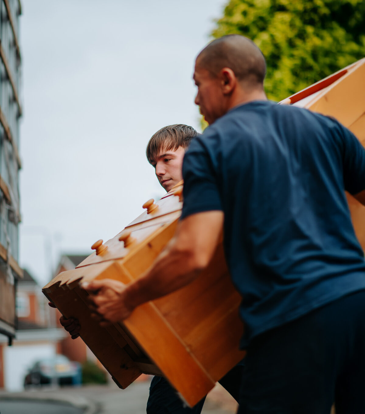 Two Ballards staff members carrying a chest of drawers