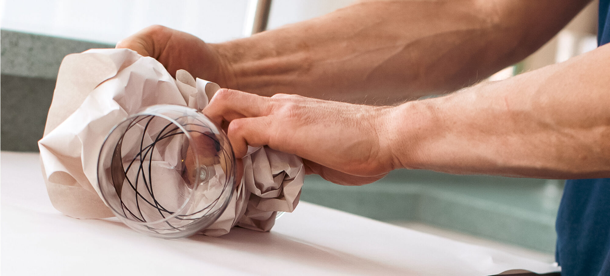 Man carefully wrapping a glass ready for removals