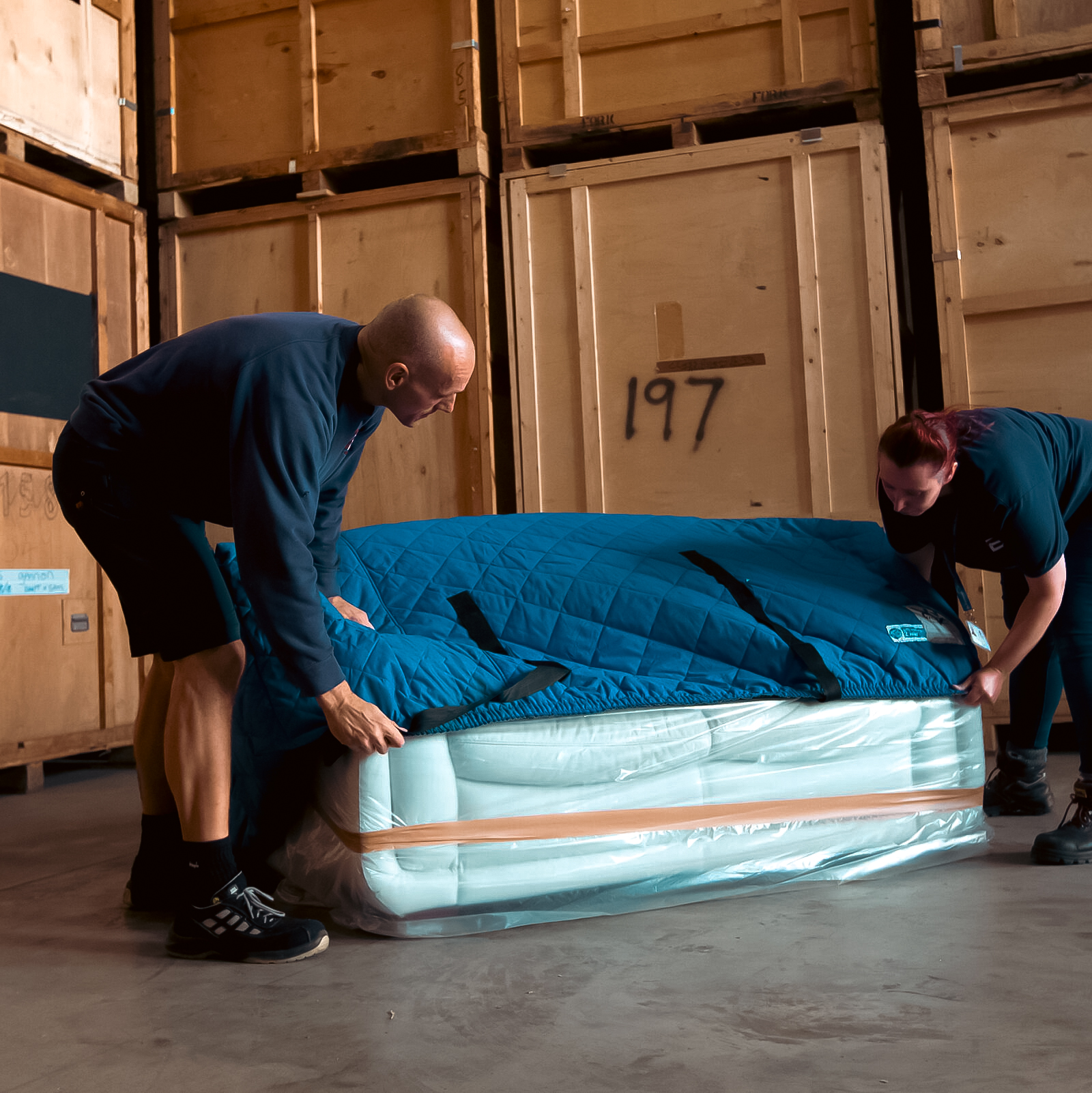 Two ballards team members putting protective covers on a sofa