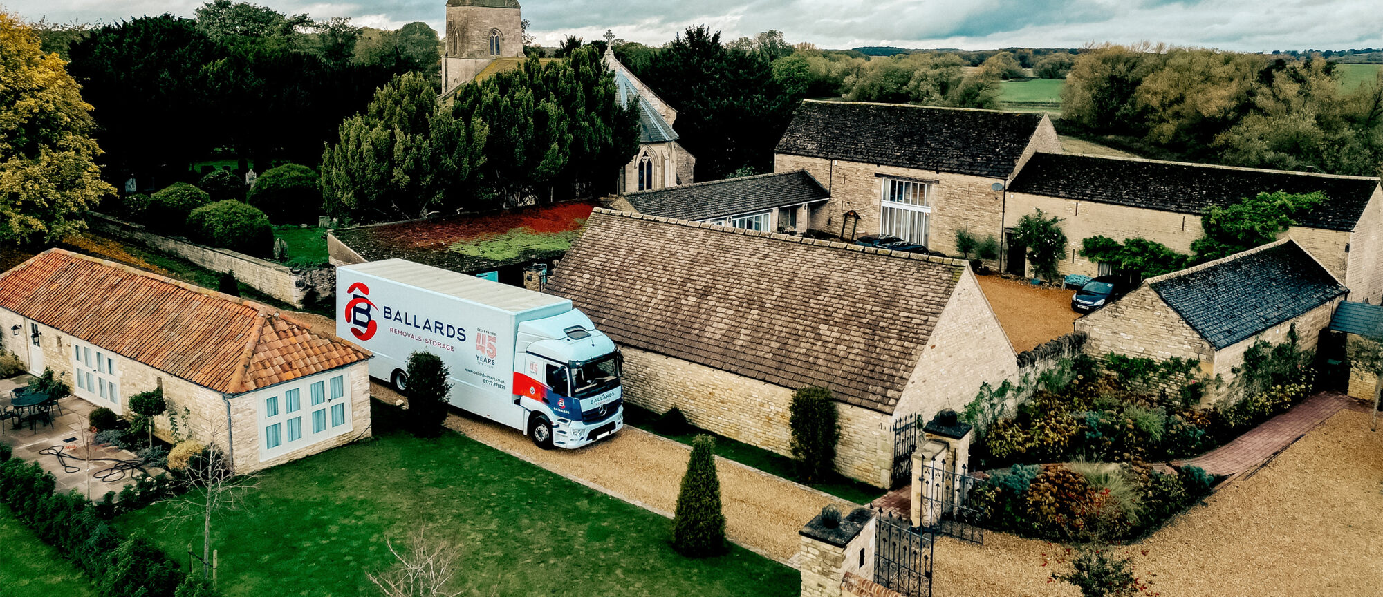 European removals - Ballards removal truck parked outside of a house with a church behind