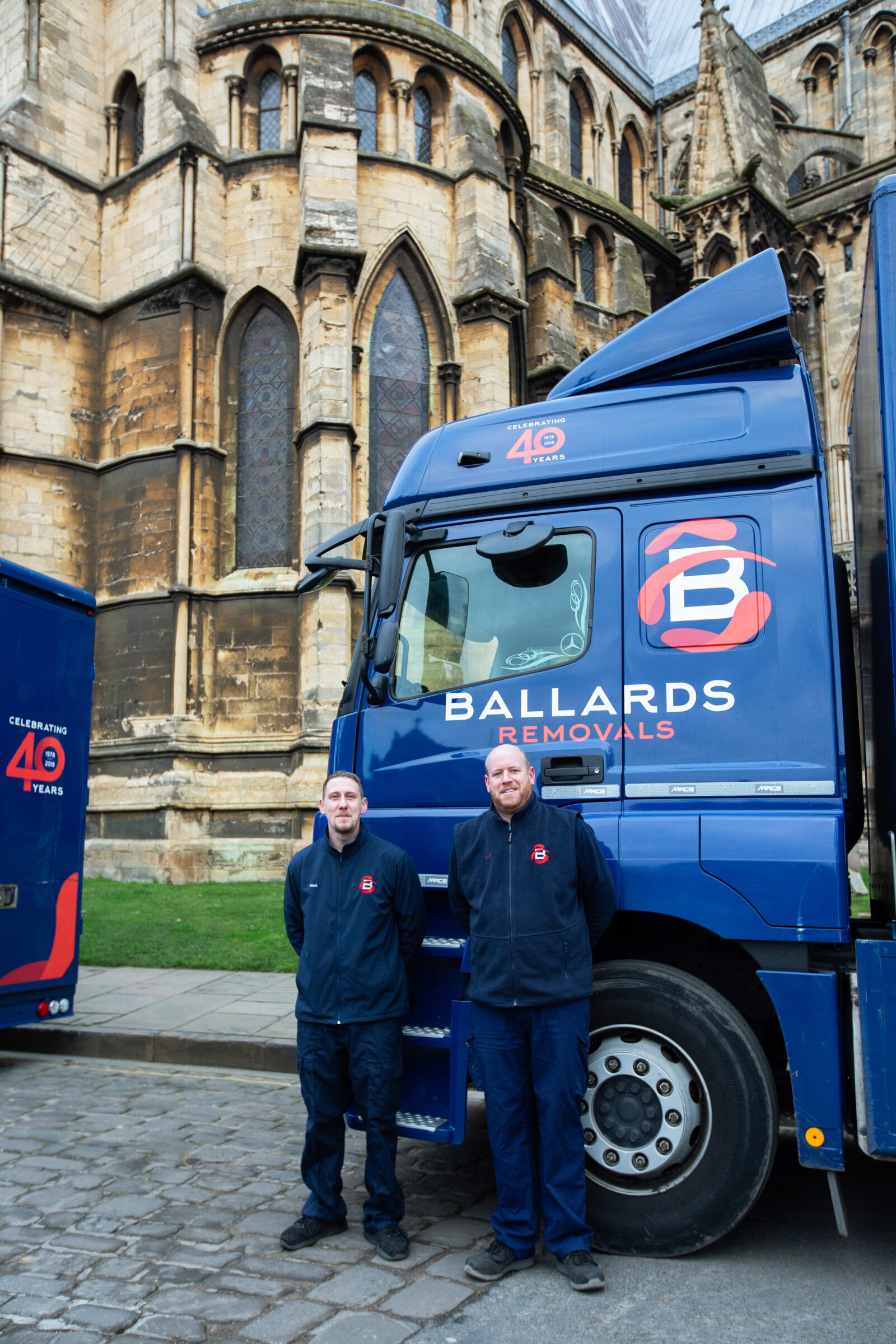 Two Ballards Removals team members standing in front of a Ballards truck parked outside Lincoln Cathedral.