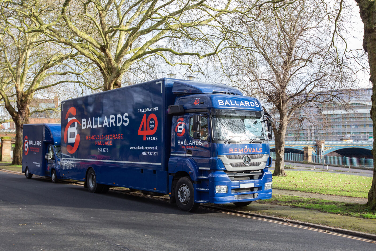 Ballards removals vehicles parked beside the riverside in West Bridgford, with the River Trent and surrounding greenery visible in the background.