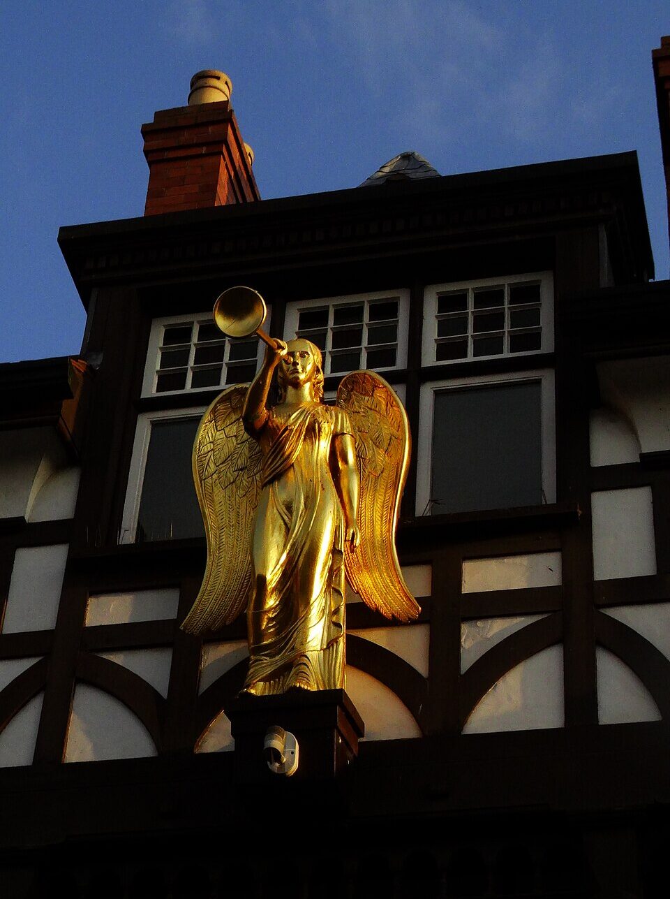 A carved golden angel figure mounted on the exterior of the Brigg Heritage Centre building, shown against brickwork with detailed architectural features.