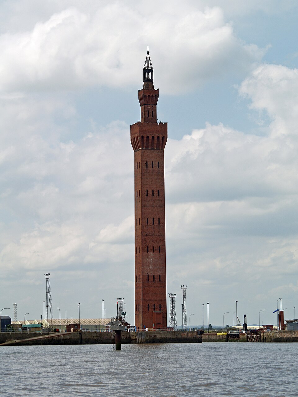 A tall brick hydraulic dock tower in Grimsby, captured from ground level, showing its detailed Victorian industrial architecture against a clear sky.