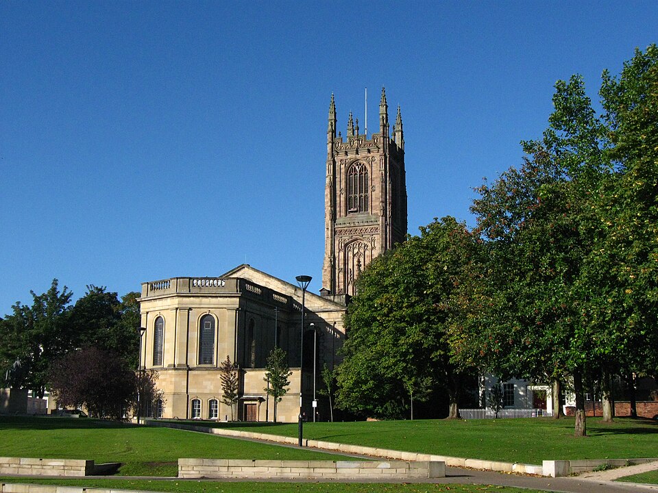 Derby Cathedral viewed from the street, showing its tower, stone façade and surrounding public space.