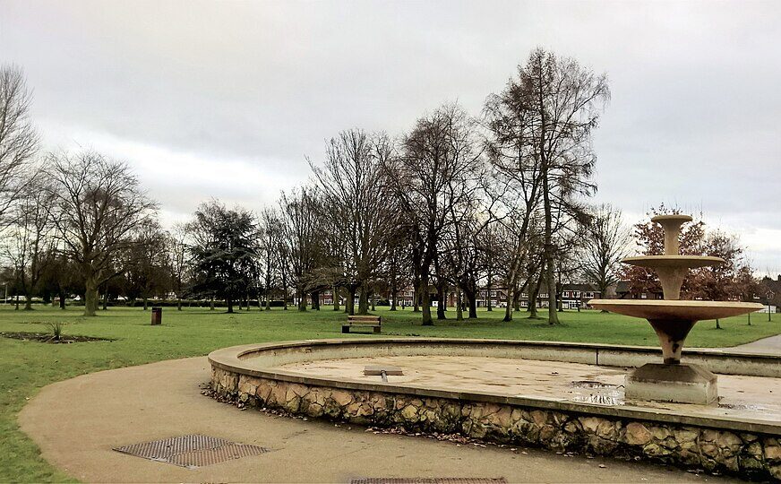 Dry fountain feature in Central Park, Scunthorpe, with surrounding paths, trees and open green space visible.
