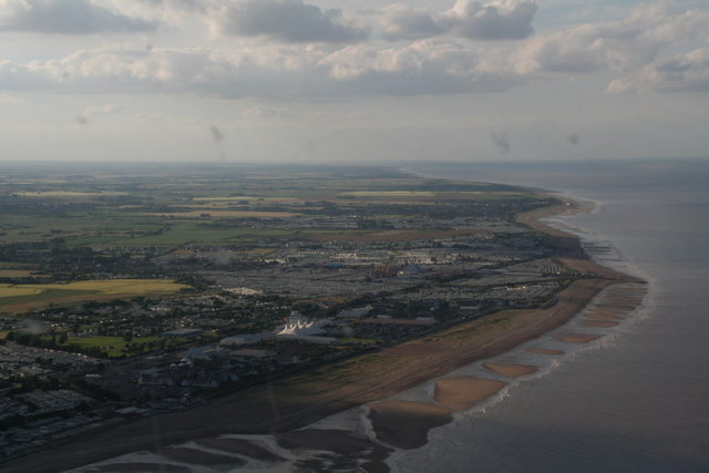 Aerial view of Skegness beach at low tide, showing wide stretches of sand, shallow water patterns and the coastline near Ingoldmells under clear summer light.